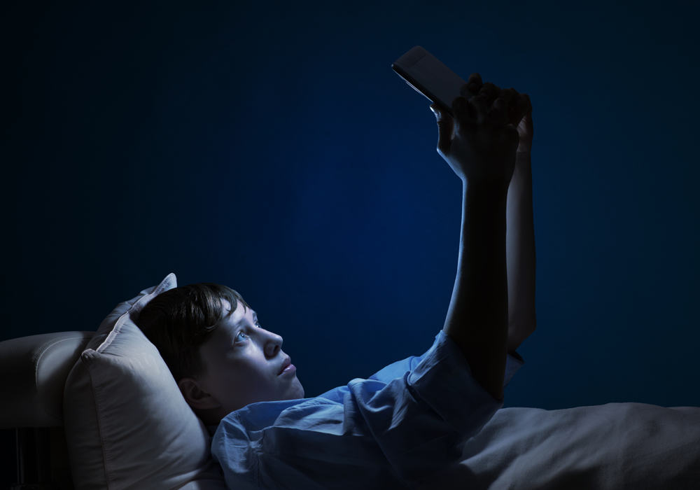 Ragazzo con smartphone a letto non riesce a prendere sonno